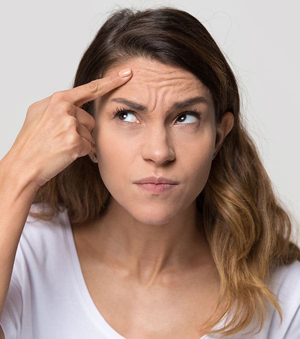 Dissatisfied stressed depressed young woman touch forehead worried about skin wrinkle isolated on studio background, cosmetology botox injection anti aging cream concept, cosmetology facial treatment