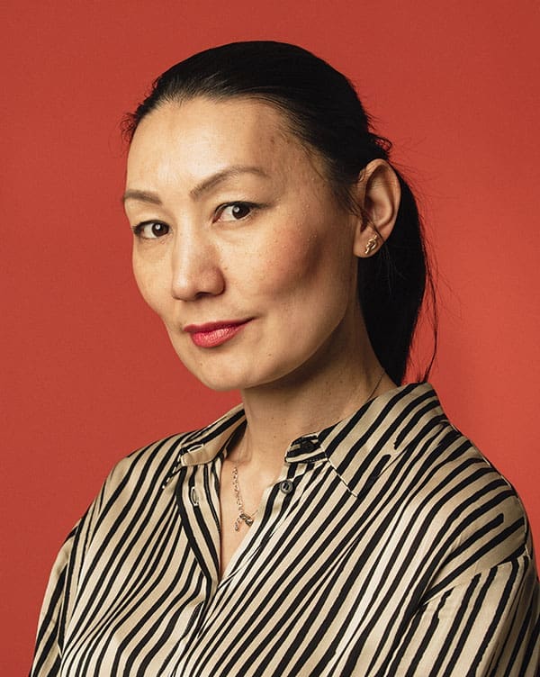 One woman standing in a studio, looking at the camera with a focused, empowered stance.