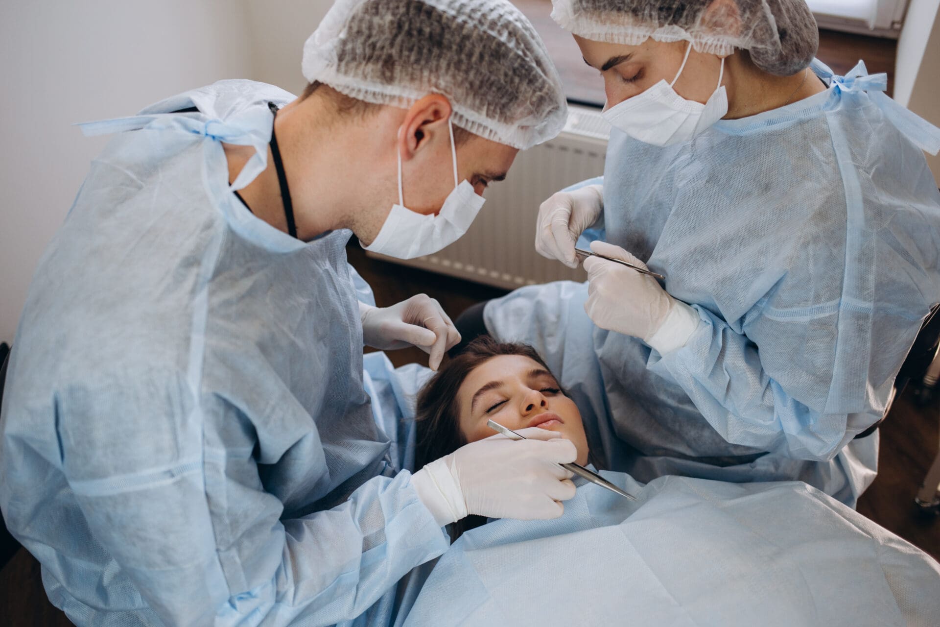 Surgeon and his assistant performing cosmetic surgery on nose in hospital operating room. Nose reshaping, augmentation. Rhinoplasty. Surgeon and his assistant performing cosmetic surgery on nose in hospital operating room. Nose reshaping, augmentation. Rhinoplasty.
